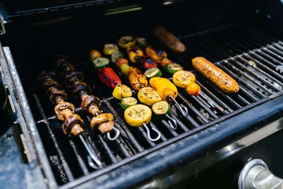 A platter of vibrant grilled vegetables, including carrots, corn, bell peppers, and eggplants, all perfectly charred and glistening.