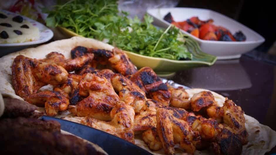 Image description: A plate of grilled chicken with visible grill marks, accompanied by grilled vegetables.